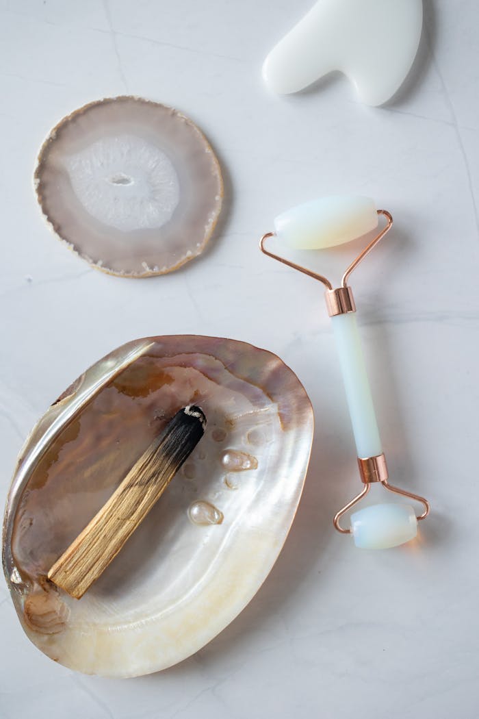 gallery-6 A luxurious jade facial roller paired with natural stones and shells for a holistic self-care ritual.