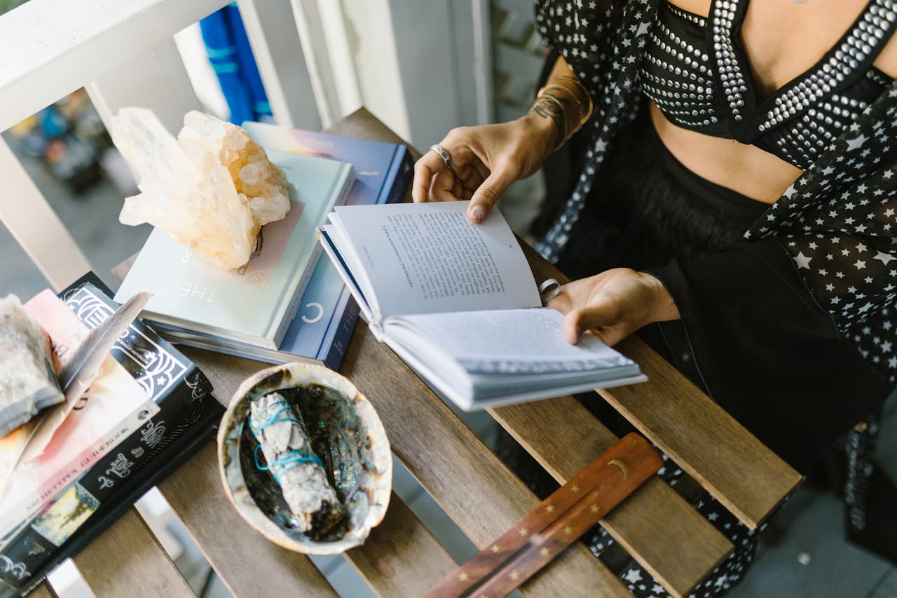 our-services-2 A person reads surrounded by crystals, sage, and books, creating a mystical atmosphere.