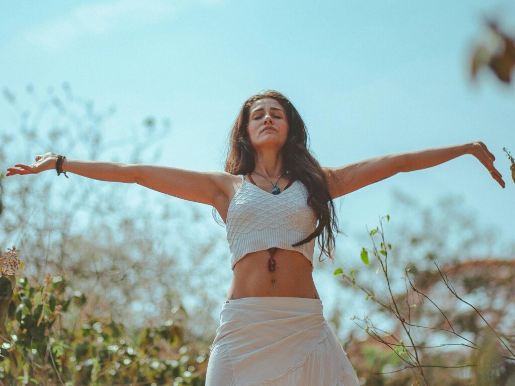 Esther Peaceful scene of a woman meditating outdoors in a sunny summer setting, embodying wellness and tranquility.